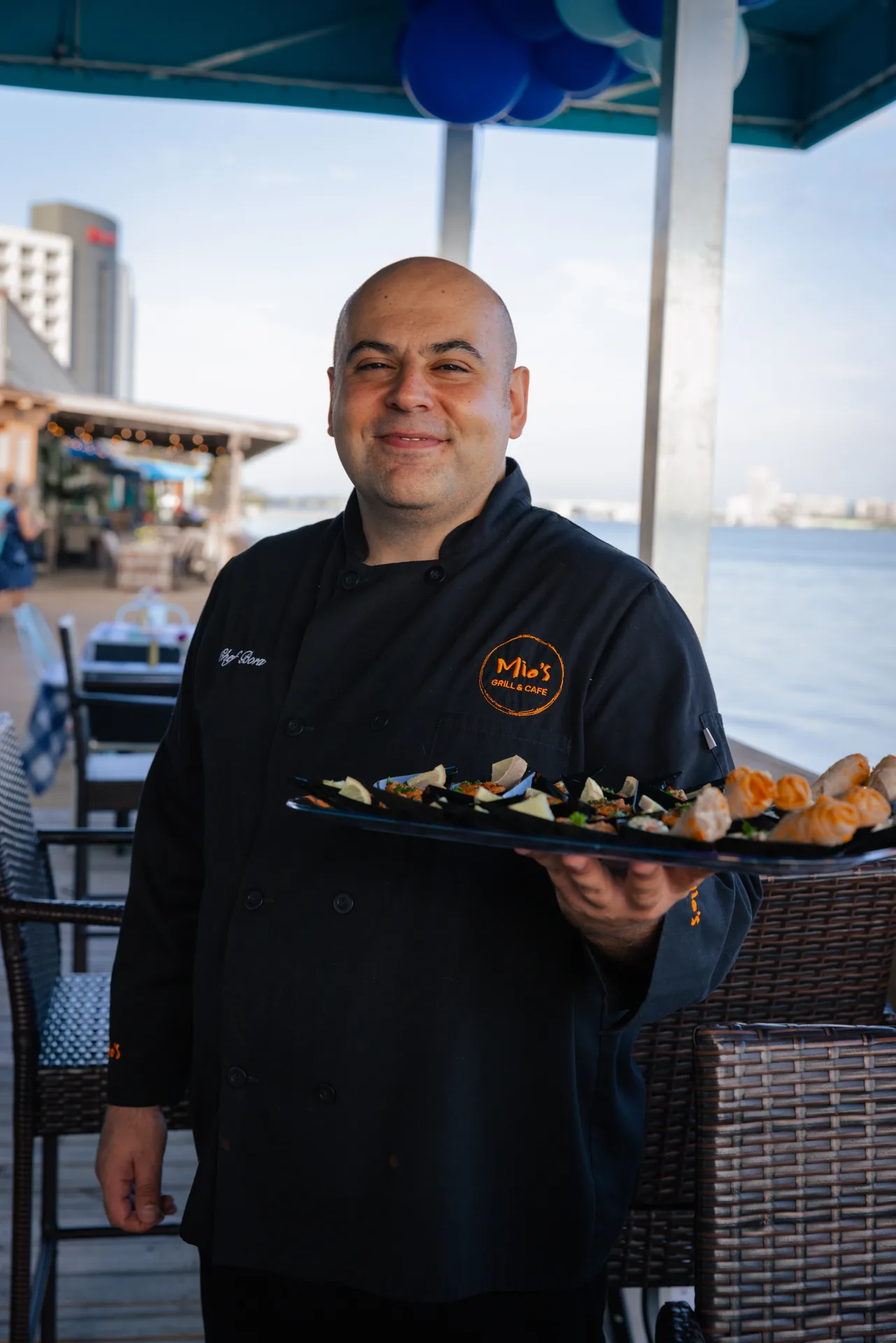 Mio's Grill & Cafe owner carrying a tray of Mediterranean dishes on Sand Key, Clearwater
